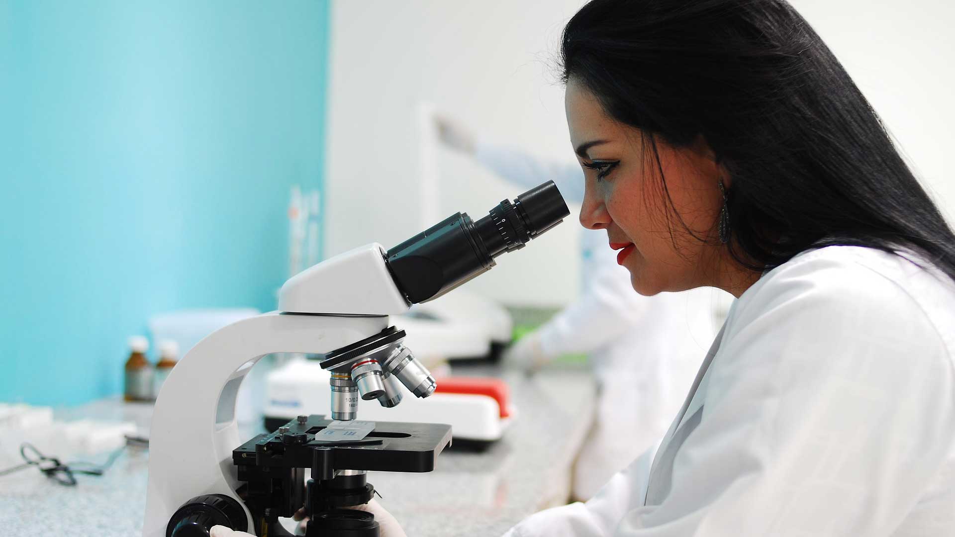 Clinical research professional using a microscope